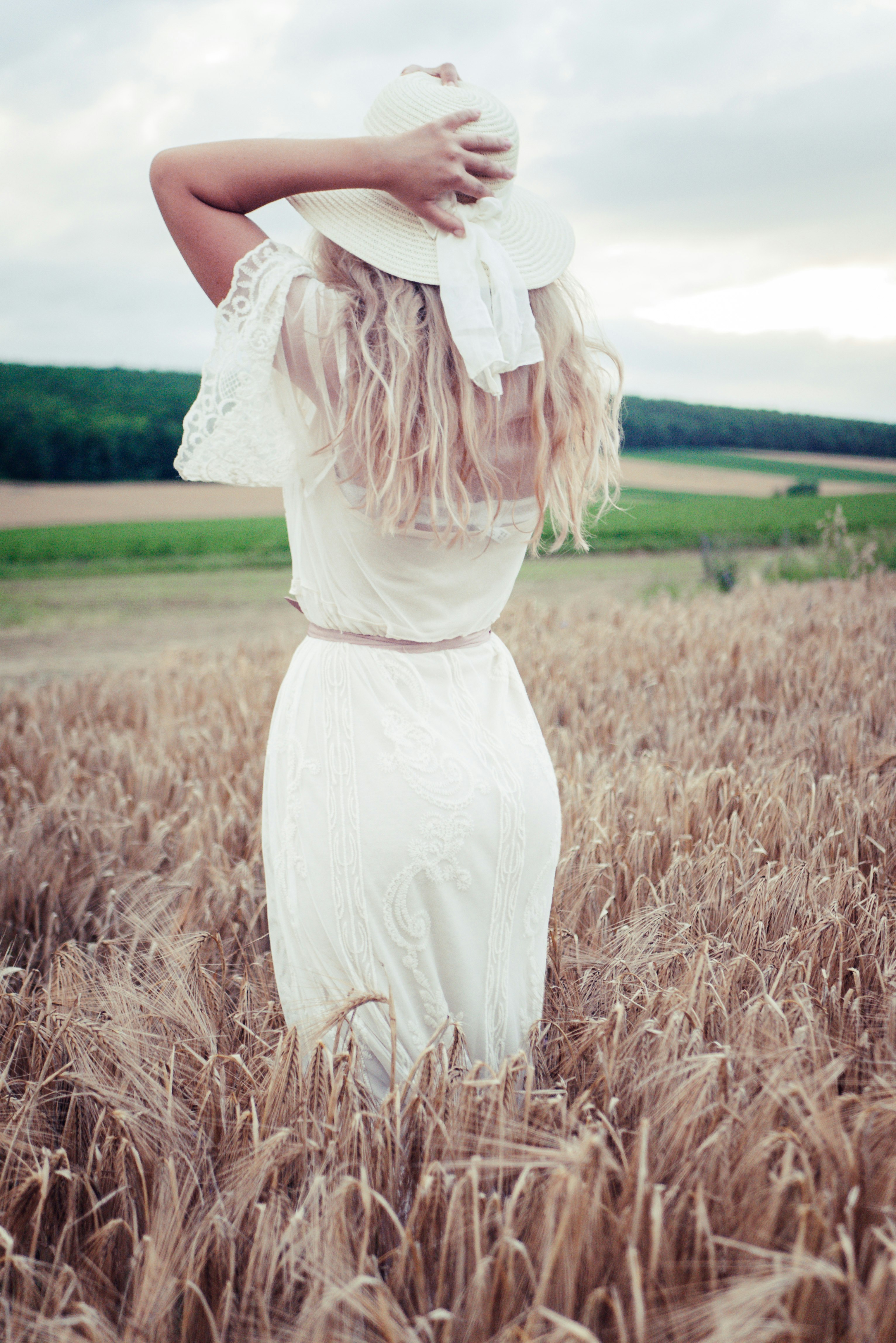 woman in white dress standing on brown grass field during daytime